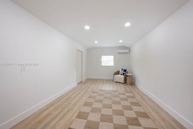 empty room with light hardwood / wood-style flooring, vaulted ceiling, and a wall unit AC