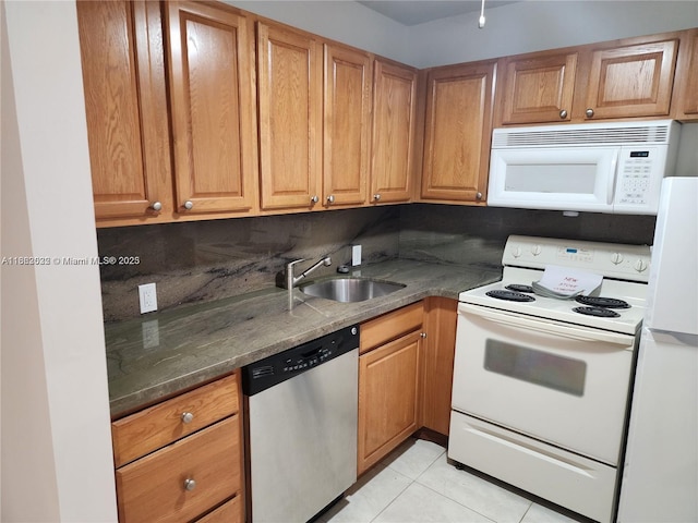 kitchen featuring sink, tasteful backsplash, dark stone countertops, white appliances, and light tile patterned floors