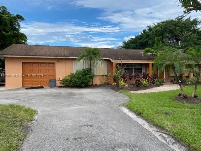 single story home with a garage and a front lawn