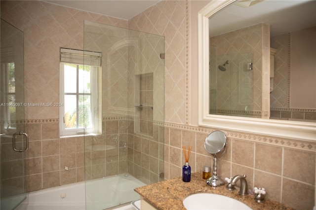 bathroom featuring tile walls, bath / shower combo with glass door, vanity, and tasteful backsplash