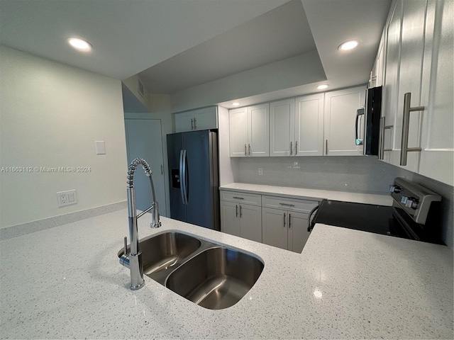 kitchen featuring sink, stainless steel appliances, light stone counters, decorative backsplash, and white cabinets