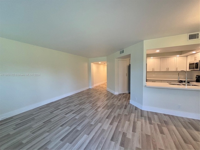 unfurnished living room with light hardwood / wood-style flooring and sink