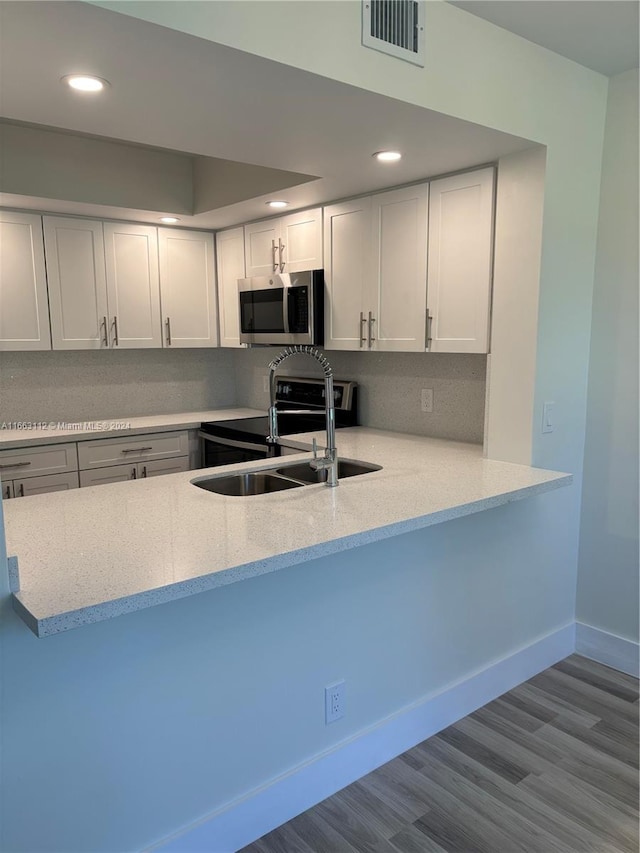 kitchen featuring kitchen peninsula, appliances with stainless steel finishes, light wood-type flooring, sink, and white cabinetry