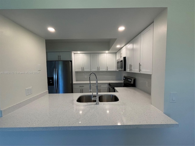 kitchen with light stone countertops, sink, white cabinets, and appliances with stainless steel finishes