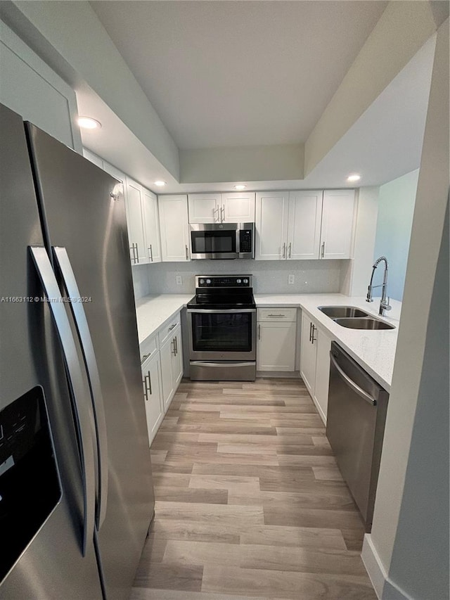 kitchen with sink, white cabinets, stainless steel appliances, and light wood-type flooring