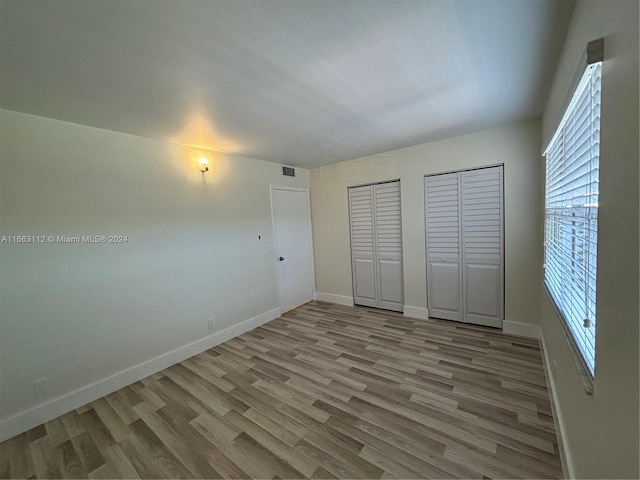 unfurnished bedroom featuring light hardwood / wood-style floors and multiple closets