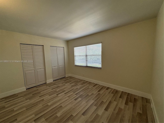 unfurnished bedroom with two closets and hardwood / wood-style flooring