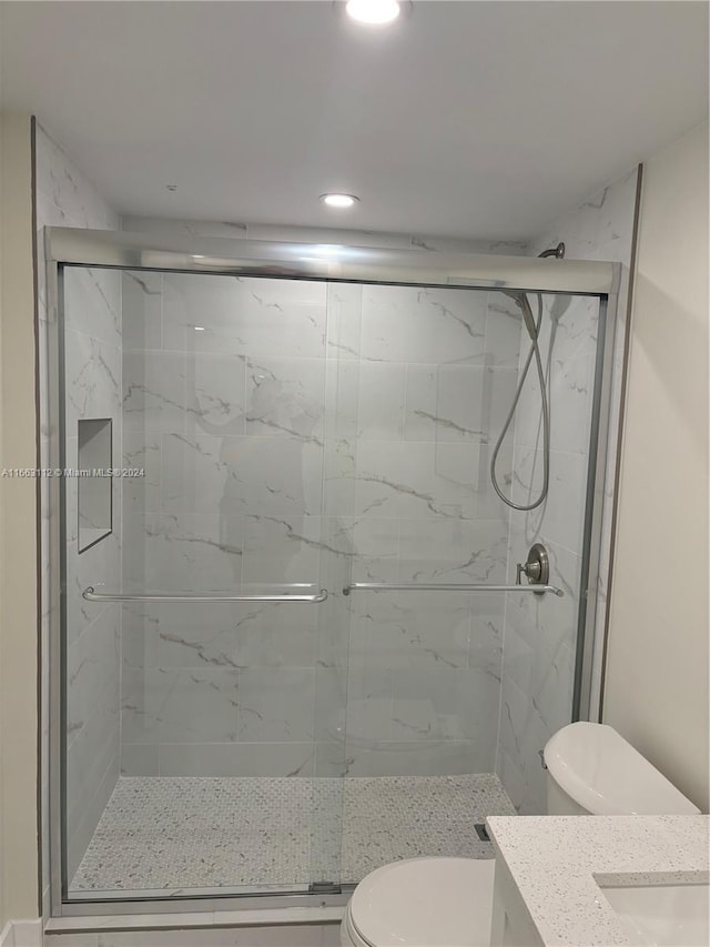 bathroom with an enclosed shower, vanity, and toilet