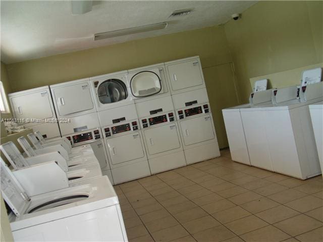 clothes washing area featuring stacked washer and clothes dryer, light tile patterned flooring, and washer and dryer