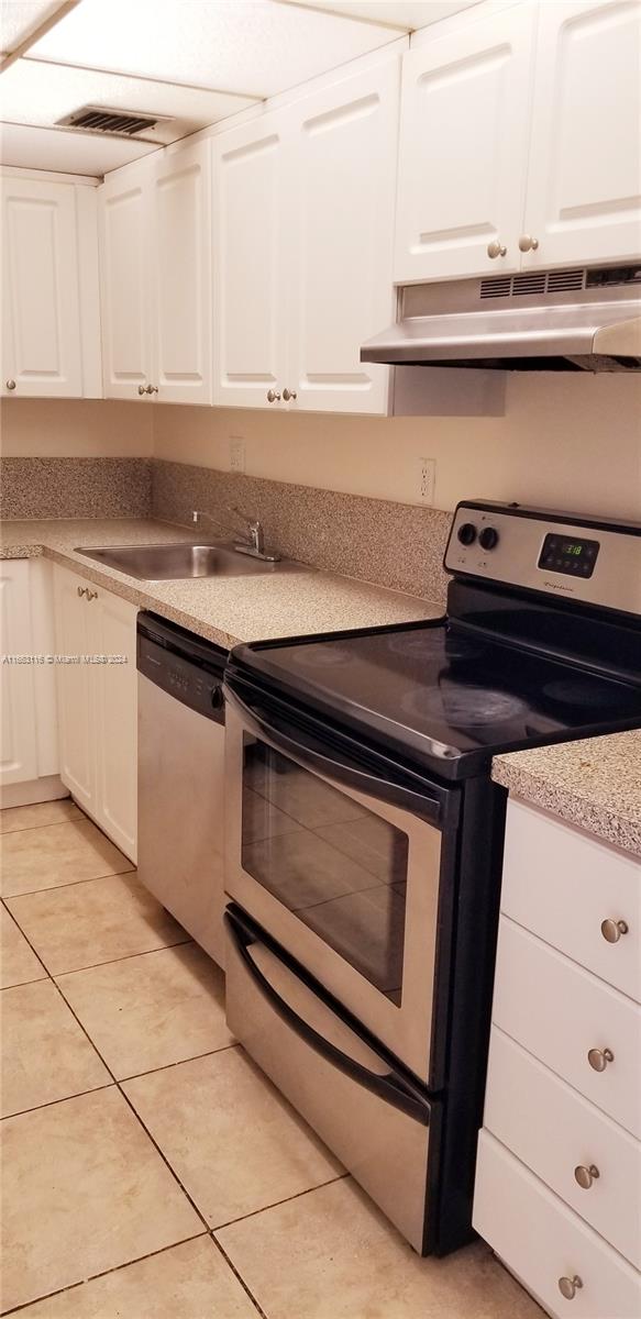 kitchen featuring sink, light tile patterned floors, stainless steel appliances, and white cabinets