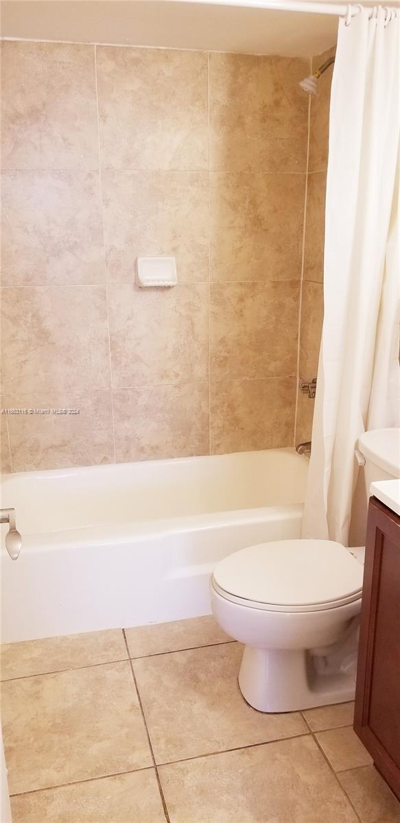 full bathroom featuring shower / bath combo with shower curtain, tile patterned floors, vanity, and toilet