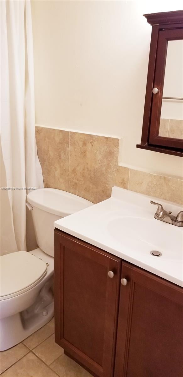 bathroom with tile walls, vanity, toilet, and tile patterned floors