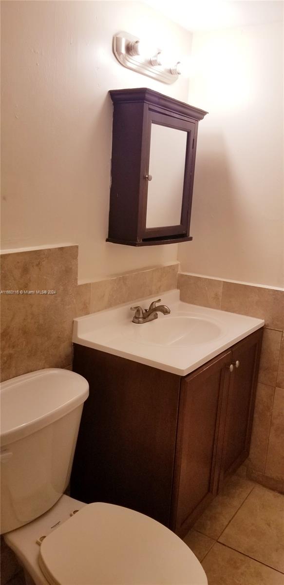 bathroom with vanity, tile walls, tile patterned flooring, and toilet