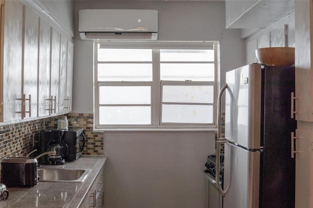 kitchen with stainless steel refrigerator, sink, decorative backsplash, and an AC wall unit