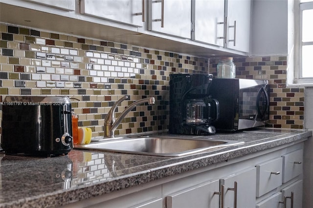 kitchen with backsplash, sink, and white cabinetry