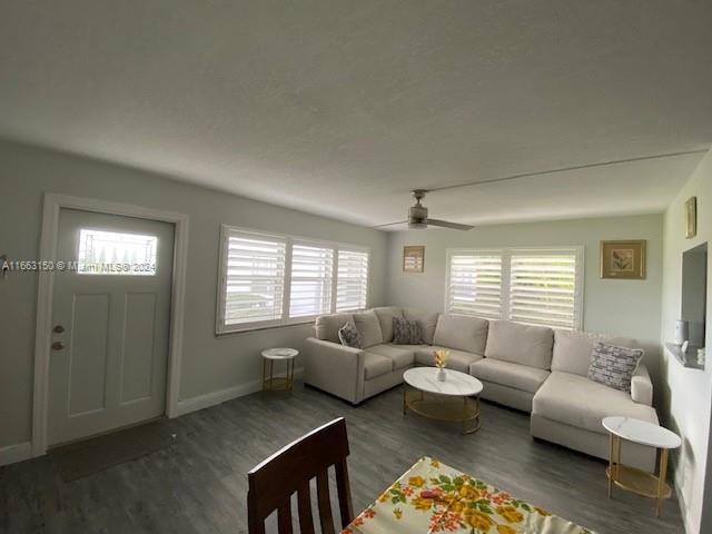 living room featuring ceiling fan and dark hardwood / wood-style floors