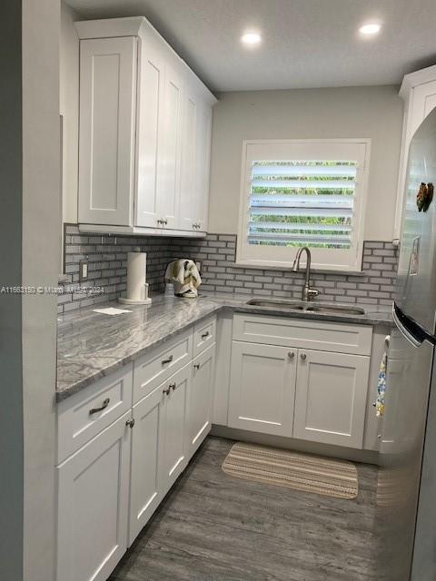 kitchen featuring white cabinets, stainless steel fridge, sink, dark hardwood / wood-style flooring, and decorative backsplash