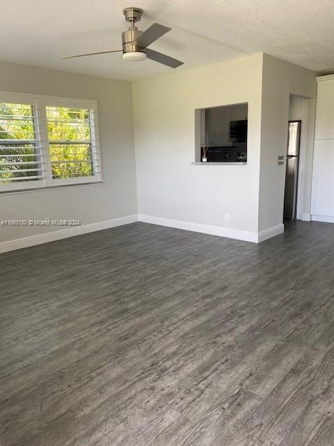 unfurnished living room with a textured ceiling, dark hardwood / wood-style flooring, and ceiling fan