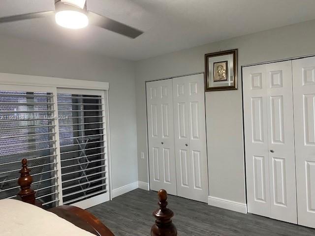 bedroom featuring two closets, dark hardwood / wood-style floors, and ceiling fan