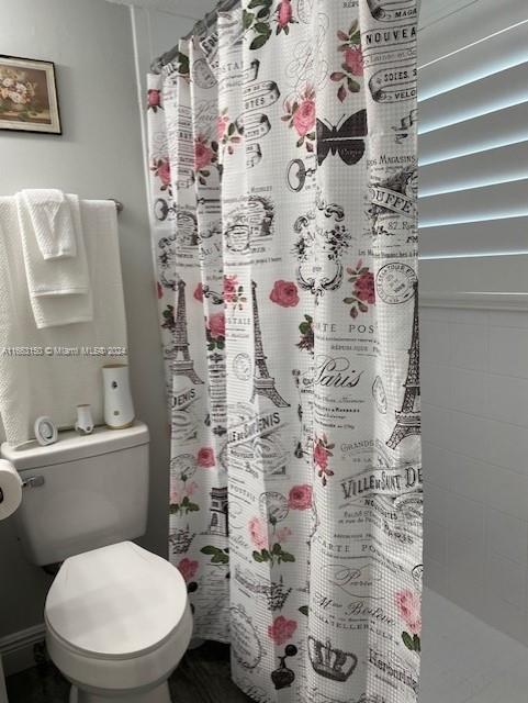 bathroom with a shower with curtain and toilet