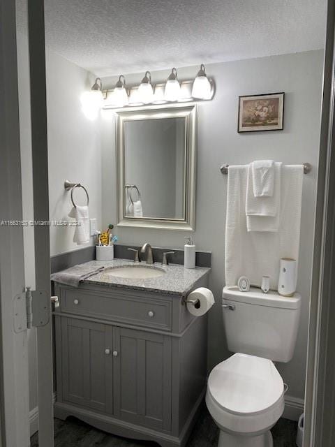 bathroom featuring a textured ceiling, vanity, and toilet