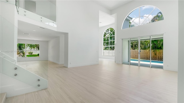 unfurnished living room featuring light hardwood / wood-style flooring and a high ceiling