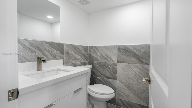 bathroom with tile walls, vanity, and toilet