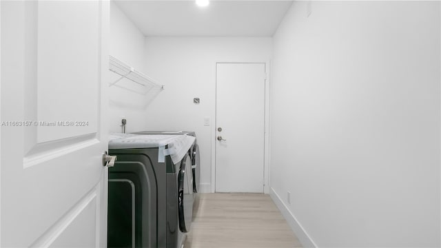 laundry room featuring washing machine and dryer and light hardwood / wood-style flooring