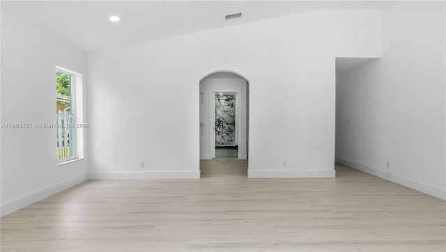 unfurnished room with light hardwood / wood-style floors and vaulted ceiling