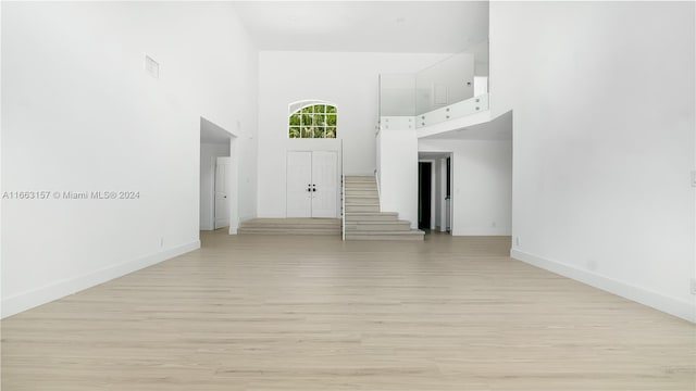 empty room with a towering ceiling and light hardwood / wood-style floors