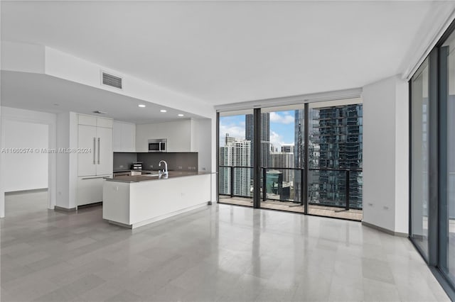 kitchen featuring floor to ceiling windows, sink, tasteful backsplash, and white cabinetry