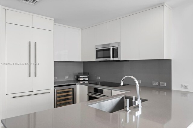 68 SE 6th St Unit 3102, Miami, FL 33131 - kitchen with wine cooler, stainless steel appliances, a sink, white cabinets, and modern cabinets