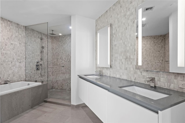 bathroom featuring shower with separate bathtub, vanity, tile walls, and tile patterned floors