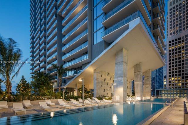 pool at night featuring a patio area