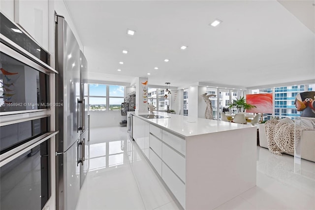 kitchen featuring white cabinetry, a large island with sink, oven, black electric stovetop, and light tile patterned floors