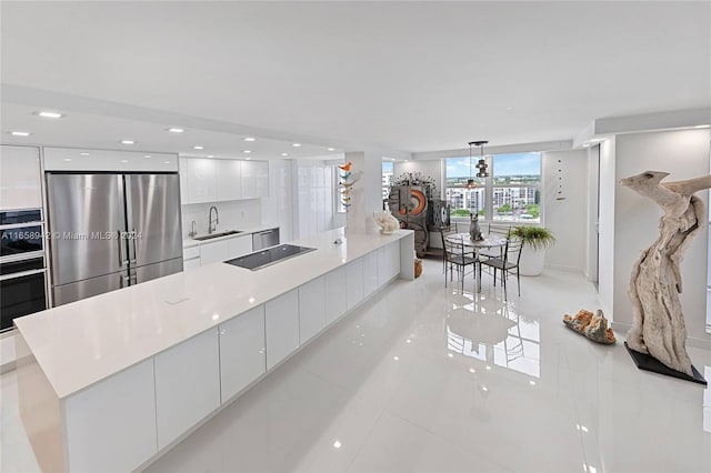 kitchen with a center island, black appliances, sink, decorative light fixtures, and white cabinetry