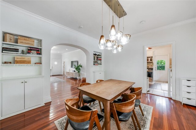 dining area featuring built in shelves, ornamental molding, and dark hardwood / wood-style floors