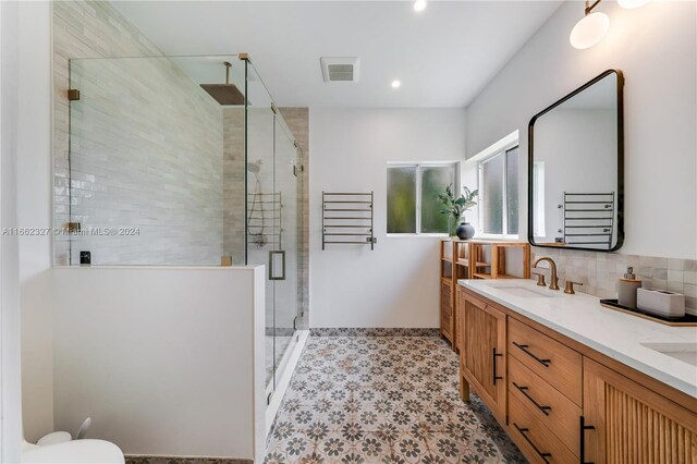 bathroom with vanity, a shower with shower door, toilet, and tasteful backsplash