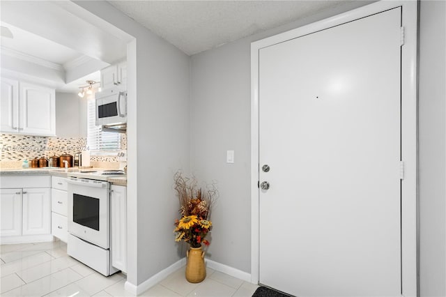 kitchen with white cabinets, backsplash, white appliances, light tile patterned floors, and ornamental molding