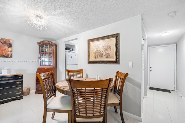 tiled dining area featuring a textured ceiling and a notable chandelier