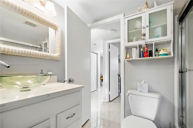 bathroom with tile patterned flooring, vanity, toilet, and an enclosed shower