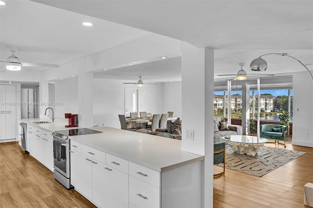 kitchen featuring sink, white cabinets, light hardwood / wood-style flooring, appliances with stainless steel finishes, and ceiling fan