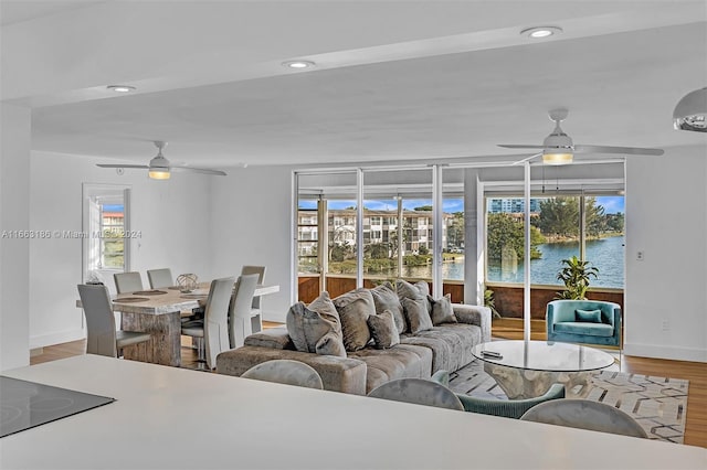 living room featuring ceiling fan, wood-type flooring, and a water view