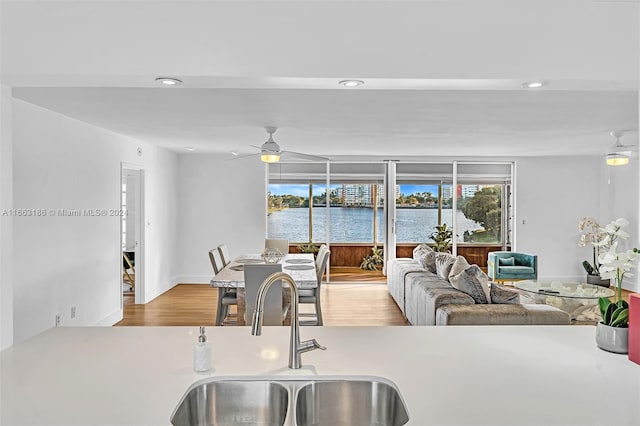 kitchen with ceiling fan, light hardwood / wood-style floors, sink, and a water view