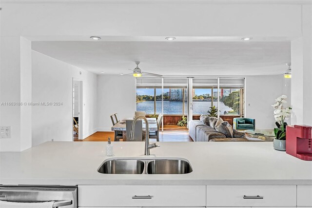 kitchen with sink, white cabinetry, a water view, ceiling fan, and stainless steel dishwasher