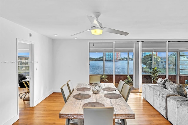 dining space with light hardwood / wood-style flooring, a water view, and ceiling fan