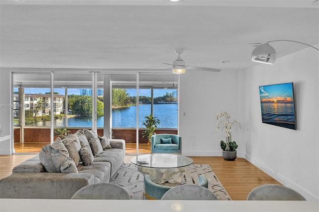 living room featuring ceiling fan, light hardwood / wood-style floors, and a water view