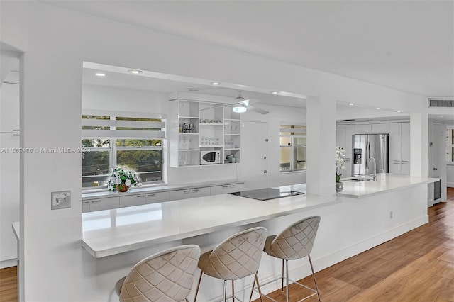 kitchen featuring light hardwood / wood-style flooring, white cabinetry, a breakfast bar, and stainless steel refrigerator with ice dispenser