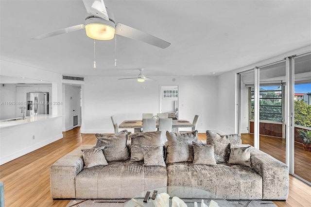 living room with ceiling fan, light hardwood / wood-style flooring, and sink