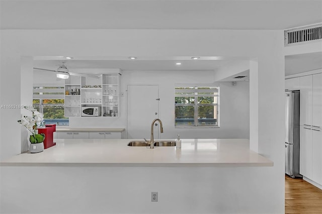 kitchen with wood-type flooring, stainless steel fridge, sink, and a healthy amount of sunlight